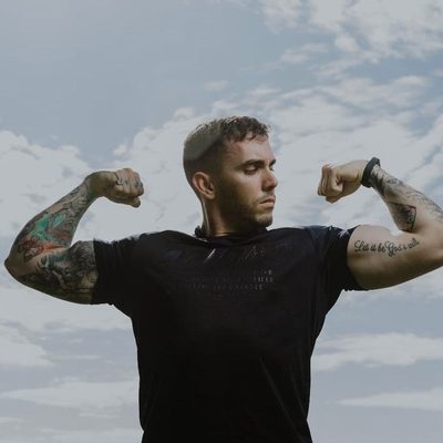 Coach Master Vein — double biceps pose against open sky